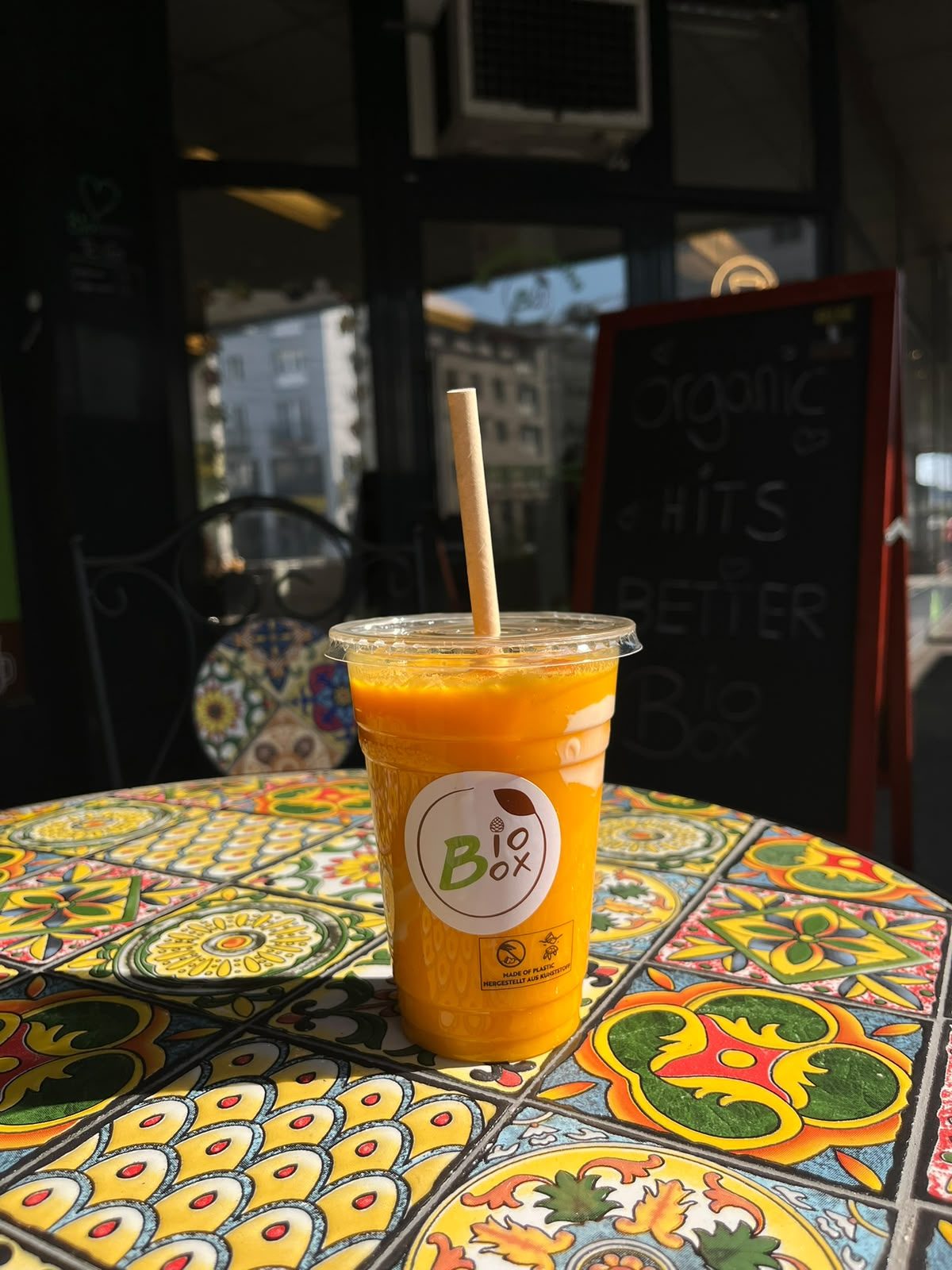 Frischer Mango-Saft auf bunter Fliese vor dem Café