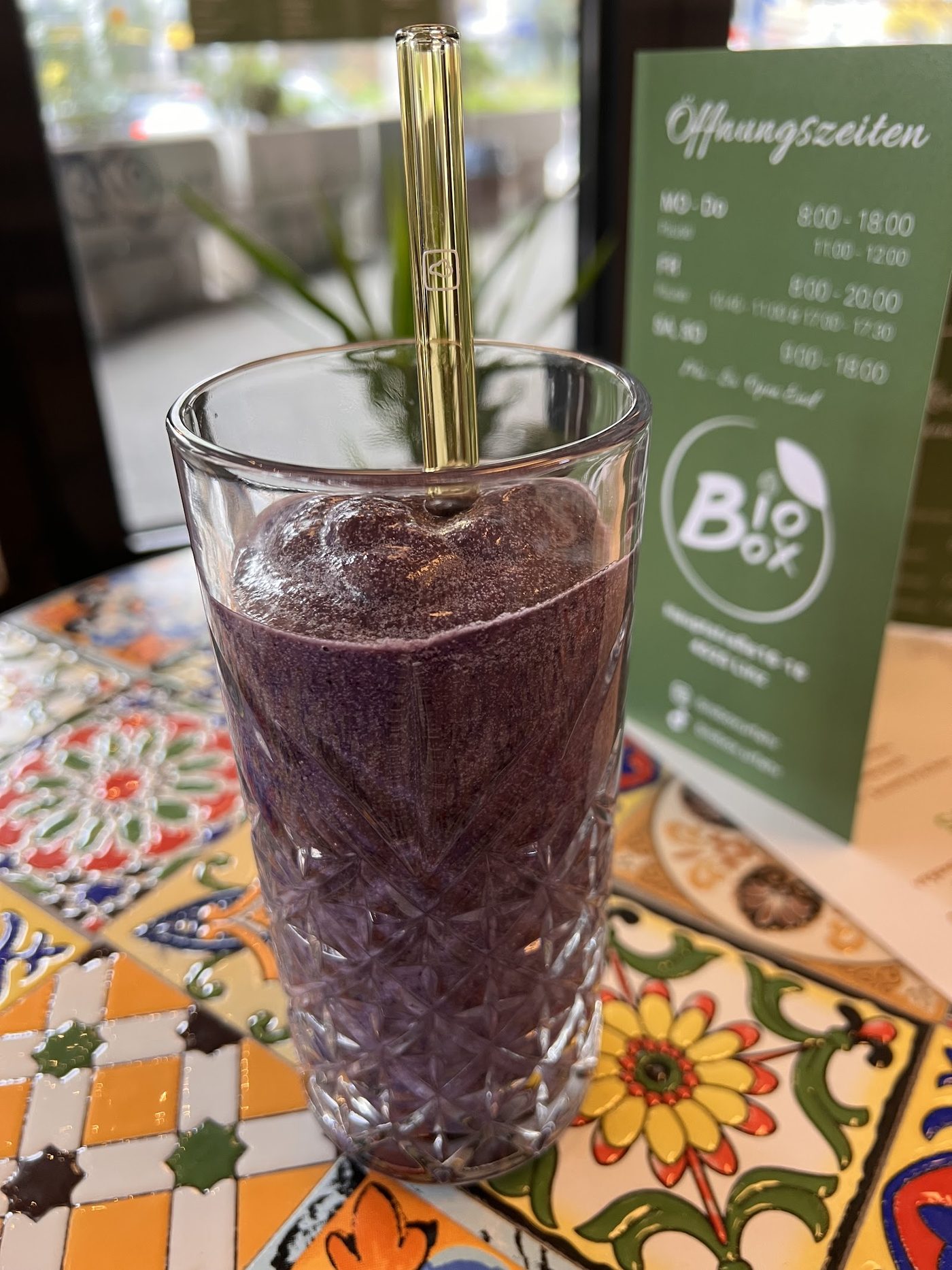 Lila Açaí-Smoothie im Glas mit goldenem Strohhalm